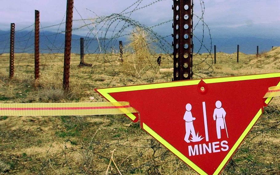 An international sign warning about mines hangs beside a minefield at Bagram Air Base on, March 22, 2002. The White House announced Tuesday a new policy curtailing the use of anti-personnel land mines by the U.S. military, reversing a more permissive stance that was enacted by former President Donald Trump. Under the policy, such explosives will still be allowed to defend South Korea against a potential attack by North Korea, but otherwise they will be banned.