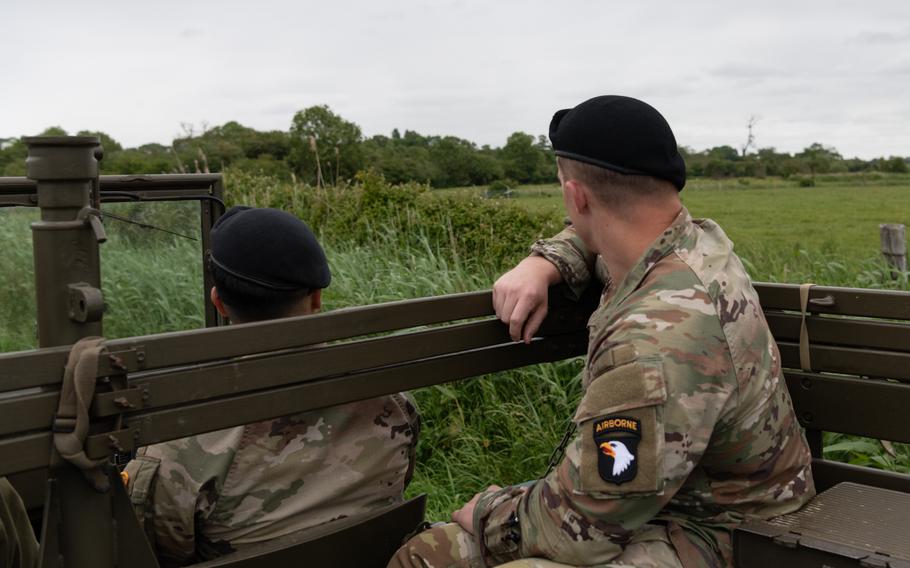 Soldiers ride in a vintage military vehicle.