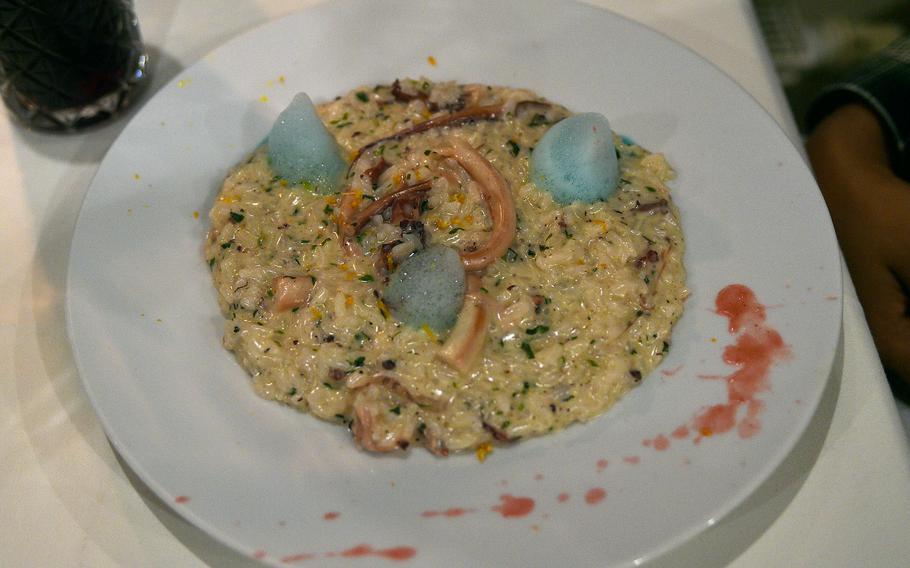 Risotto in a wide white bowl with red drizzle.