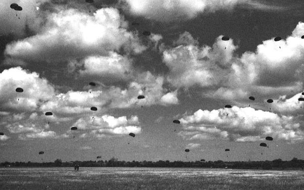 Amfreville, Normandy, France, June 5, 1994: Parachutes glide towards earth as some 550 paratroopers reenacted the 101st Airborne Division D-Day jump. Nineteen of them are veterans of the actual landing 50 years ago who had fought to liberate the small town of Ste. Mère-Église. They were the first to jump, together with 22 other WWII combat paratroop veterans. 
They preceded about 500 active-duty American and French paratroops. The American paratroops were from the 101st and 82nd Airborne division, and the 3rd Battalion, 325th Airborne Battalion Combat Team in Vicenza, Italy. All landed in a 300-acre drop zone in Amfreville, about 3 miles from Ste.Mère-Église.

Read Stars and Stripes reporter Philip H. Bucknell's 1944 eyewitness account from that jump, published in Stars and Stripes' London edition, June 14, 1944 here. 

META TAGS: DDAY80; World War II; WWII; D-Day;  anniversary; paratroop; reenactment; airborne