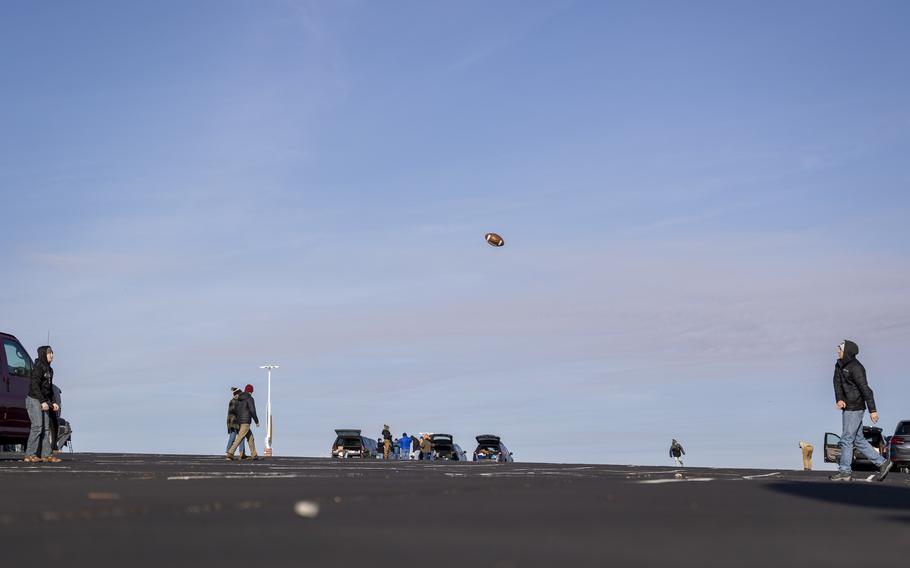 A football flies across the parking lot from thrower to receiver.