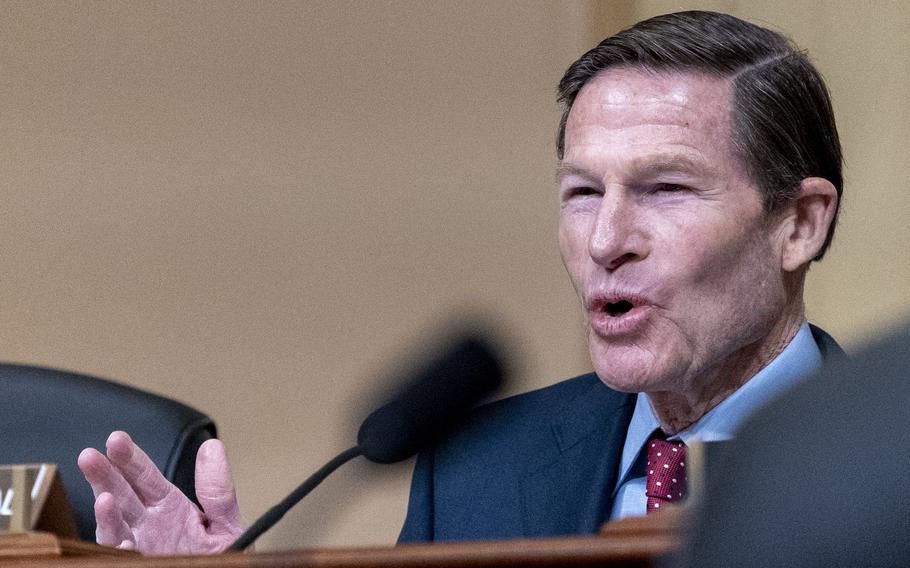 A congressman in a blue suit sits and speaks into a microphone during a hearing.