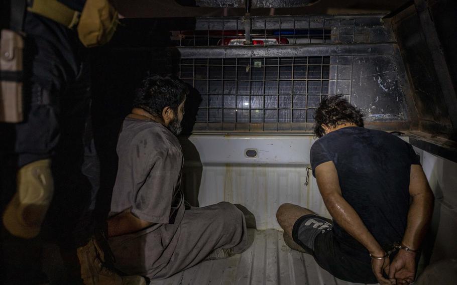 Suspected drug dealers sit in handcuffs following their Aug. 18 arrest in Basra, Iraq. The drug trade in Iraq is protected by powerful armed groups, some of them linked to Iran, as well as tribal networks and corrupt officials, according to Iraqi security, border and judicial officials.