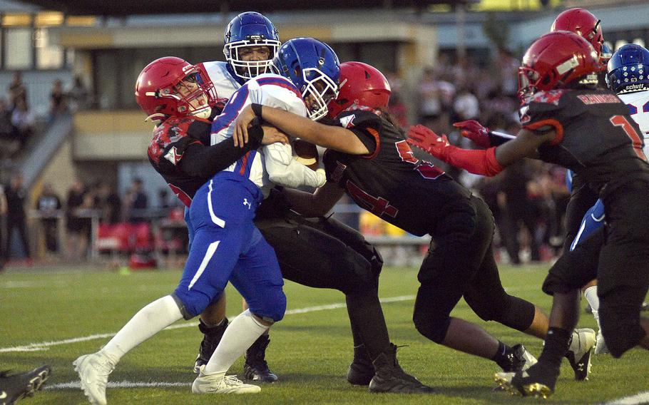 A pair of Raiders, including senior Julian Murdock, center right, gang up on Ramstein running back Ethan Wilson during a Sept. 15, 2023, game at Babers Stadium in Kaiserslautern, Germany. Kaiserslautern defeated the Roayls, 27-24.