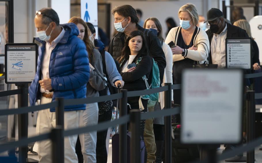 Passengers wait in line at the security checkpoint at Ronald Reagan Washington National Airport, Tuesday, April 19, 2022, in Arlington, Va. The Justice Department is filing an appeal seeking to overturn a judge’s order that voided the federal mask mandate on planes and trains and in travel hubs. The notice came minutes after the Centers for Disease Control and Prevention asked the Justice Department to appeal the decision handed down by a federal judge in Florida earlier this week.