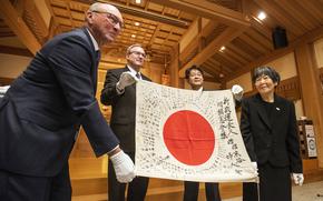 A U.S. Marine’s family returns a “good luck flag” to the family of a Japanese sailor during a ceremony Sunday, Dec. 4, 2022, at Gokoku-jinja, a shrine dedicated to the spirits of Hiroshima’s war dead.