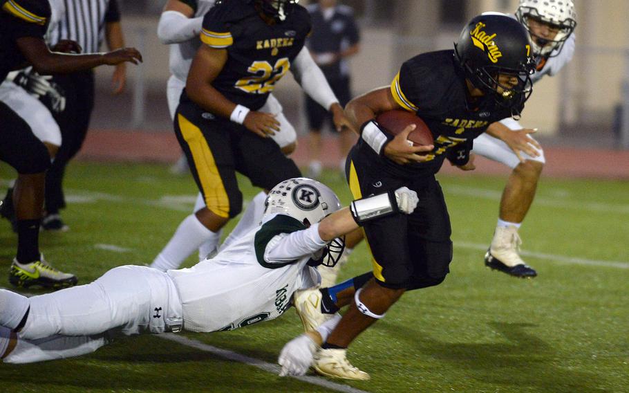 Kadena quarterback Cameron Wilson tries to elude the grasp of Kubasaki defender Caleb Stefan.