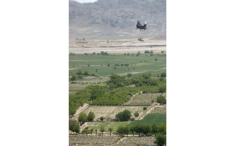 A CH-47D Chinook from Company G, 104th Aviation Regiment flies over an Afghan farm as it delivers a sling-loaded Humvee from Kandahar to a firebase at Deh Rawood. During their 10 months in Afghanistan in 2003-2004 the crew has flown more than 8 ¾ million pounds of cargo either in its helicopter or slung underneath.