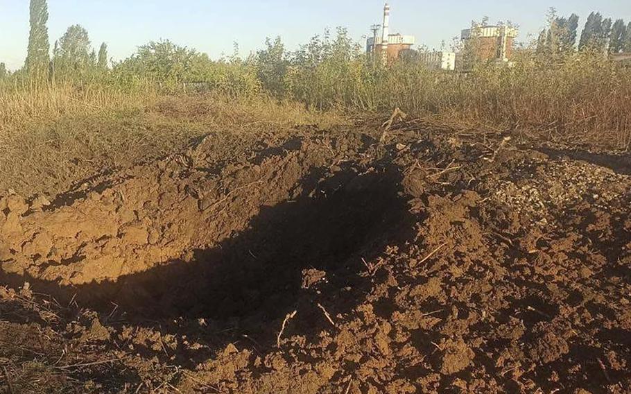 In this photo provided by the South Ukraine nuclear power plant, a crater left by a Russian rocket is seen 300 meter from the South Ukraine nuclear power plant, in the background, close to Yuzhnoukrainsk, Mykolayiv region, Ukraine, Monday, Sept. 19, 2022.