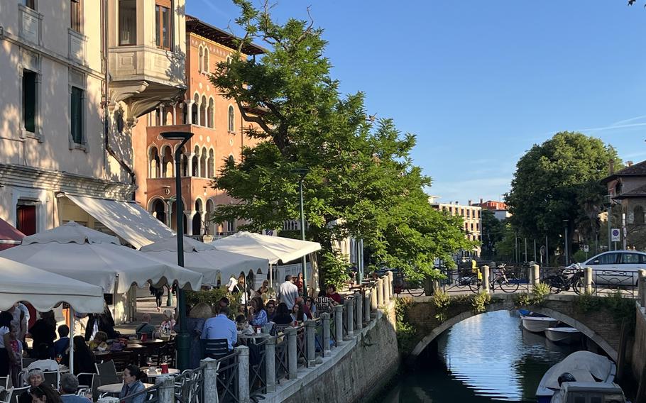 People dine along a canal in Venice, Italy.