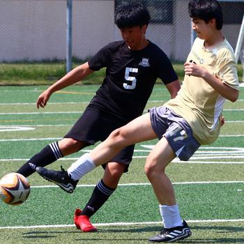 Daegu's Andrew Im and Humphreys' Thomas Torress try to play the ball during Saturday's DODEA-Korea soccer match. The Blackhawks won 4-0.