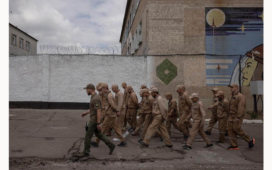 Inmates walk in a prison yard during a media event promoting a government offer to recruit some convicts for the military, in a prison colony in the Kyiv region, Ukraine, May 30, 2024.