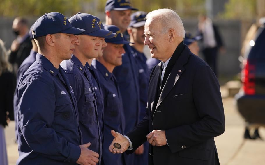 President Joe Biden hands out a challenge coin as he speaks with members of the coast guard at the United States Coast Guard Station Brant Point in Nantucket, Mass., Thursday, Nov. 25, 2021. (AP Photo/Carolyn Kaster)