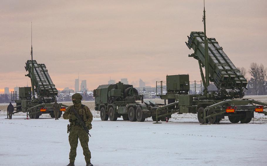 A soldier stands in front of PATRIOT (Phased Array Tracking Radar to Intercept on Target) surface-to-air missile systems during a military exercise at Warsaw Babice Airport, Poland on Feb. 7, 2023.