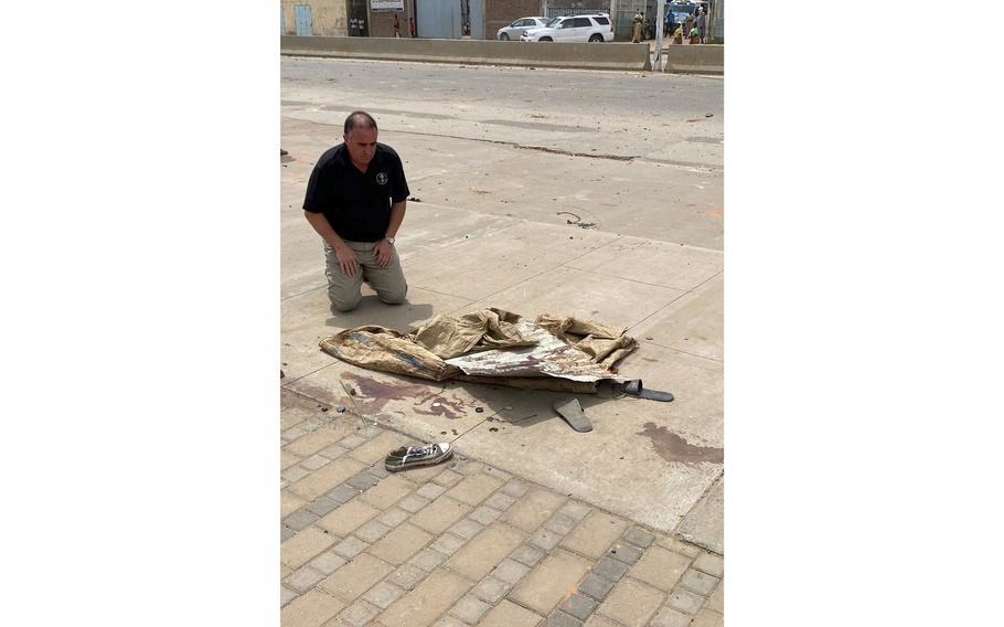 U.S. Ambassador Alexander Laskaris kneels on a bloodstained sidewalk in N’Djamena.