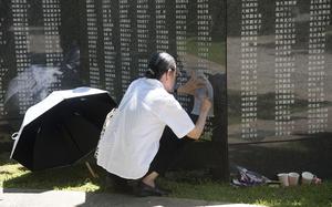A visitor makes a rubbing of a name on the Cornerstone of Peace monument at Peace Memorial Park in Itoman, Okinawa, June 23, 2025.
