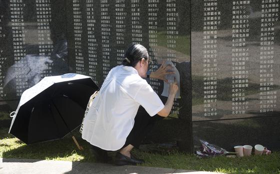 A visitor makes a rubbing of a name on the Cornerstone of Peace monument at Peace Memorial Park in Itoman, Okinawa, June 23, 2025.