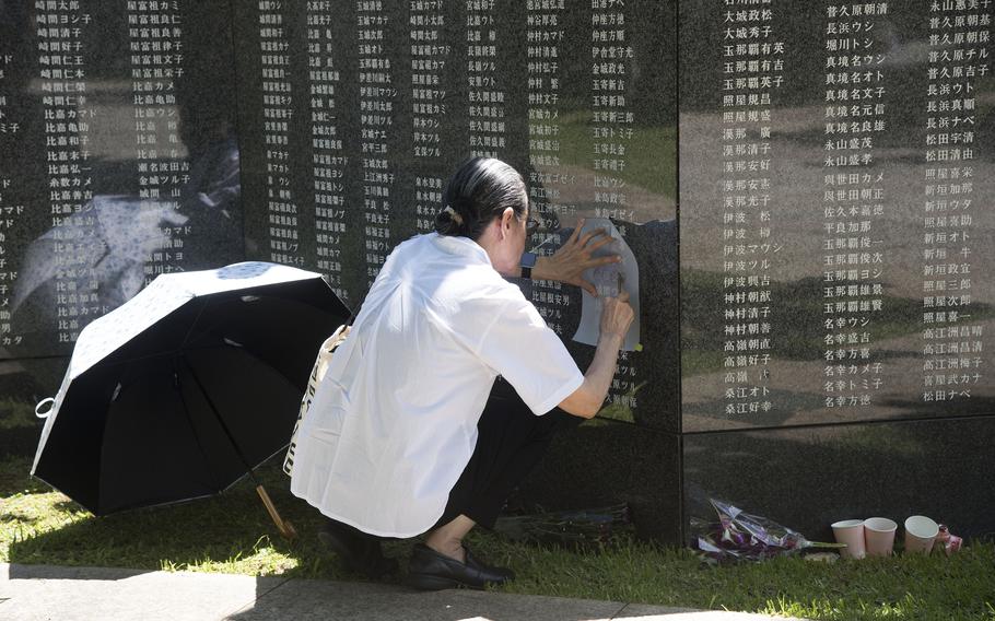 A visitor makes a rubbing of a name on the Cornerstone of Peace monument.