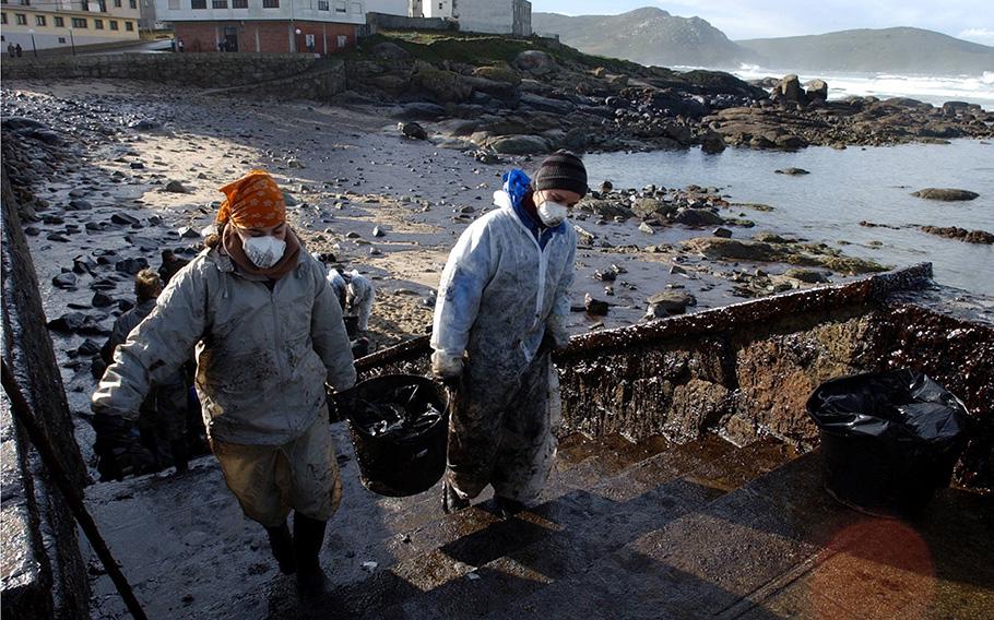 Volunteers carrying buckets of petrol in Muxia, northwestern Spain, following the sinking of the Prestige oil tanker off Spain, on Nov. 23, 2002.