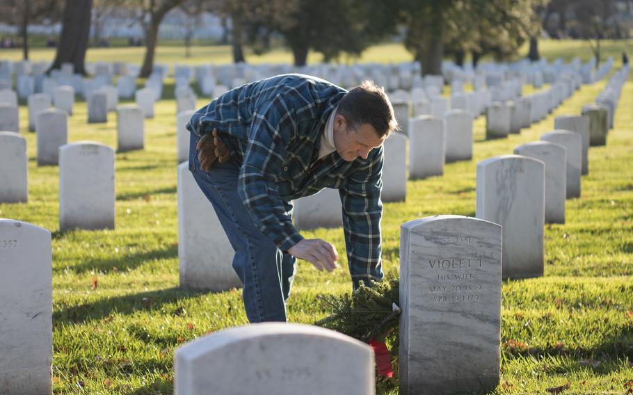 After strolling around a plot of ground, "just looking for a nice spot," Marine veteran Joe McNamara lays a wreath at the tombstone of a Marine Gunnery Sgt. at Arlington National Cemetery on Saturday, Dec. 17, 2022. "It spoke to me," he said of his choice.