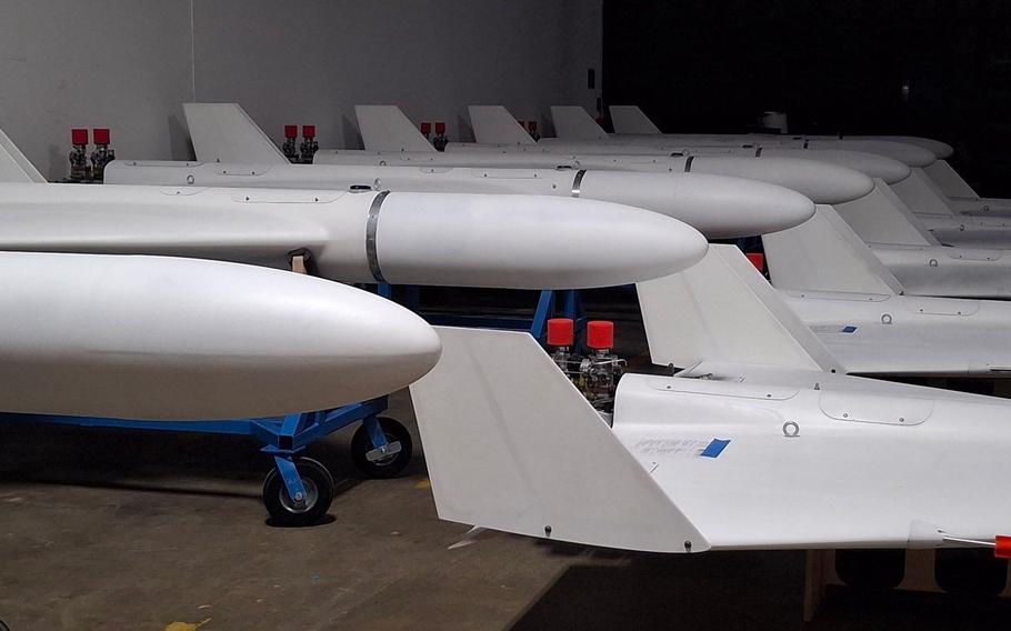 Two rows of white drones, one row on an elevated platform above the other row.