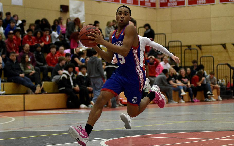 Ramstein's Ky'ron Hall picks up the ball in the lane on the fast break during a game against the crosstown rival Raiders on Jan. 31, 2024, at Kaiserslautern High School in Kaiserslautern, Germany.