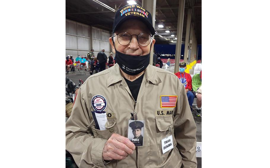 Michael Greico, 95, who shipped out from San Diego to Saipan in the spring of 1944 and later to Okinawa, poses with a photo of himself as a young Marine at Joint Base Pearl Harbor-Hickam, Hawaii, Tuesday, Dec. 7, 2021.