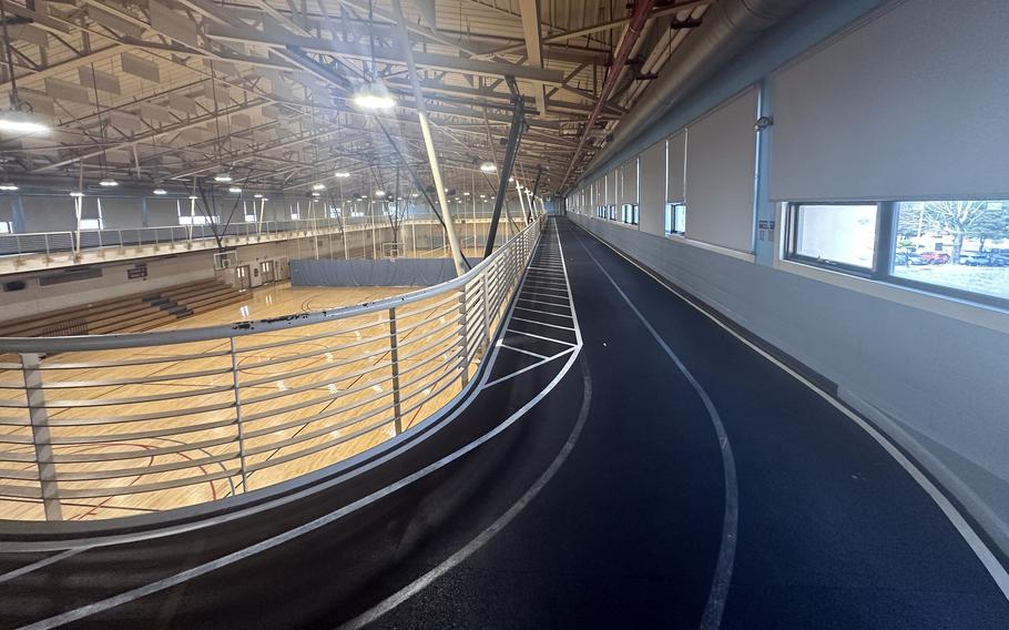 A dark blue running track situated on a balcony overlooking a basketball court below.