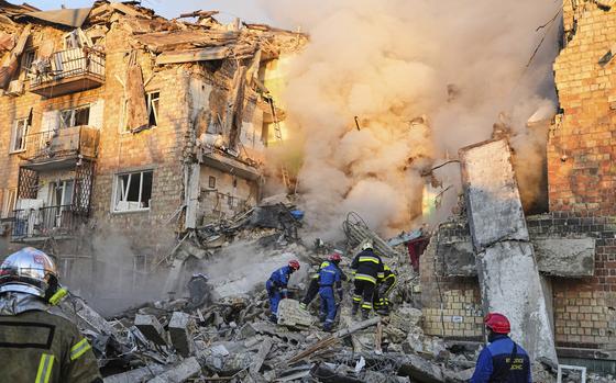 Emergency responders clime the wreckage of a partially collapsed building.