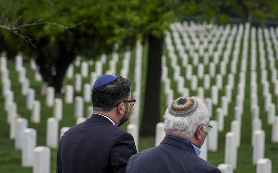 Two people with yarmulkes overlook a cemetery.
