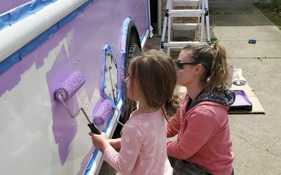 Army Sgt. Melanie Cumbie, a veterinary technician at Whiteman Air Force Base, Mo., paints the family's ice cream truck with her daughter Charlie, 6. 