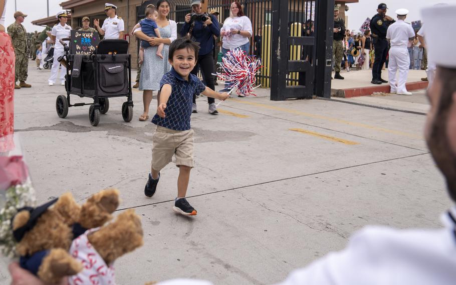 A child runs to a sailor.