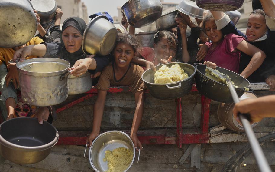 Palestinians trying to get donated food while it is being handed out in small portions