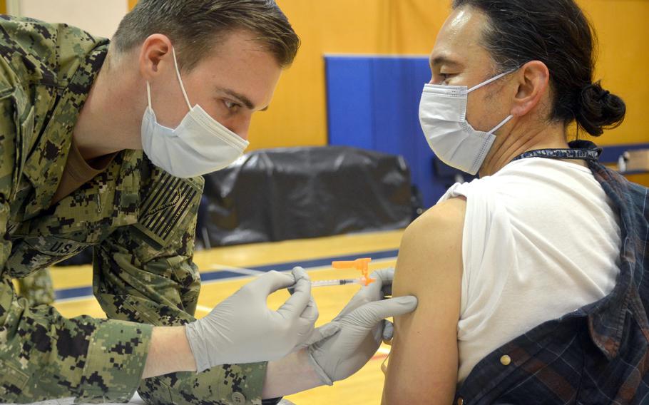 Seaman Bennett Josephson, 23, of Rochester, N.Y., gives a COVID-19 booster shot to Tomonori Ishizuko during clinic for Japanese employees at Yokosuka Naval Base, Japan, Friday, Jan. 28, 2022. 