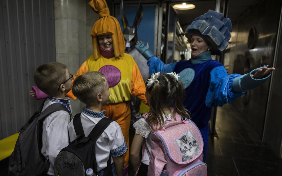 Women dressed in costumes welcome first grade students before escorting the children to their classroom in the underground metro station in Kharkiv, Ukraine.