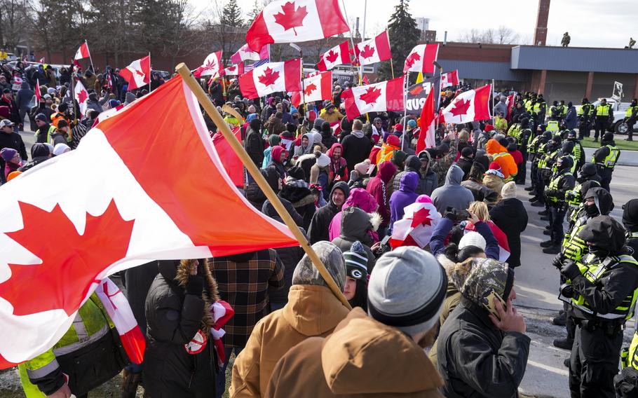 Police officers hold a line as protesters march in Windsor, Ontario, on Saturday, Feb. 12, 2022.  The demonstrations at the Ambassador Bridge, downtown Ottawa and elsewhere have targeted vaccine mandates and other coronavirus restrictions and vented fury toward Prime Minister Justin Trudeau, who has called the protesters just a “fringe” element of Canadian society.  