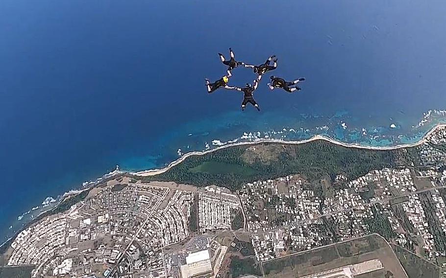 A video screen grab shows members of the U.S. Army Parachute Team skydiving over Puerto Rico.