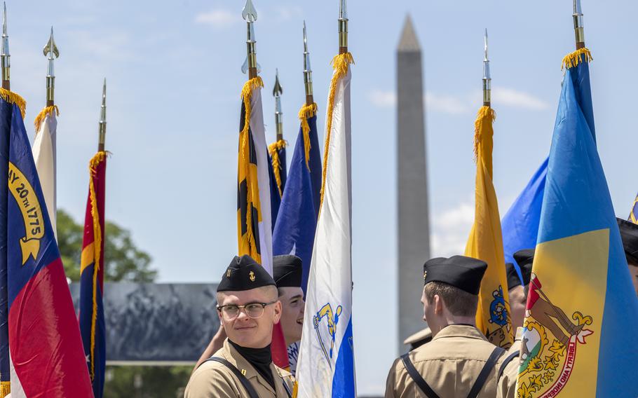 Two teens stand anong a group of flags.