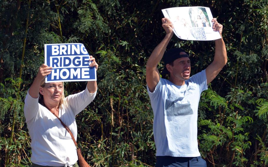 Lisa and Seth Hannemann hold up signs of support for imprisoned Navy Lt. Ridge Alkonis outside the front gate of Camp H.M. Smith in Honolulu, Wednesday, Aug. 31, 2022.