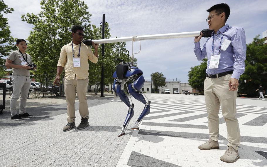 Penn Engineering Doctoral student William Yang, right, and Engineering student Zachary Francis, middle, carry the biped robot “Cassie,” as doctoral student Yu-Ming Chen uses the controls to move the robot’s legs during the Penn Engineering and Applied Sciences of General Robotics, Automation, Sensing and Perception Lab (GRASP) Technical Tours at the Pennovation Center.