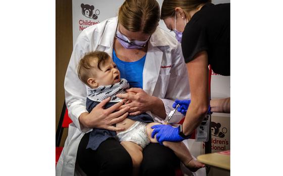 Physician Sarah Schaffer Deroo calms her 7 month-old-son, Hewitt, as he receives a coronavirus vaccine in D.C. MUST CREDIT: Washington Post photo by Bill O'Leary.