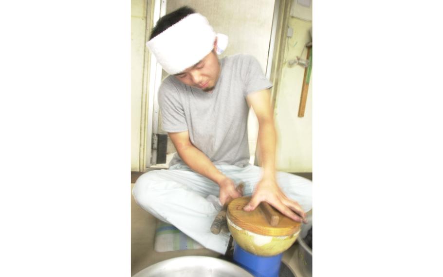 Toshikazu Kosuge taps the outside shell of the firework to settle the black powder balls into place, forming a tight fit.