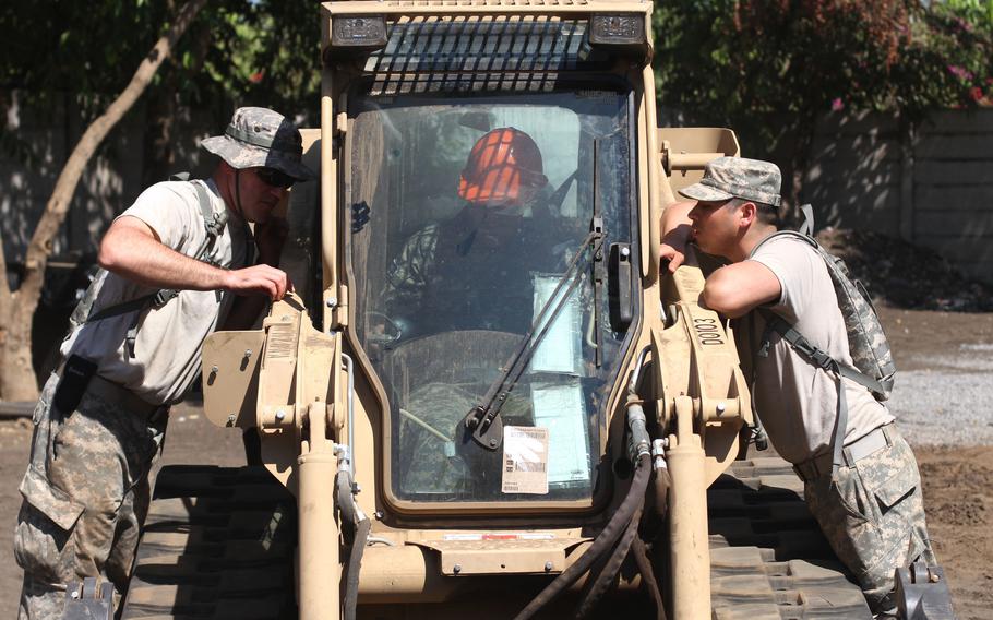 Spc. Phillip Hackley, from Nixa, Mo., and Spc. Ramiro Rodriguez, from Hollister, Mo., combat engineers with the 294th Engineer Company out of Nixa, Mo., instruct an El Salvadoran soldier on how to use the skid-steer, a light weight construction vehicle, on March 31, 2015, in Nuevo Consumidero, El Salvador. The Missouri Army National Guard’s 294th Engineer Support Company is preparing to deploy for between 10 months and a year to the Horn of Africa.