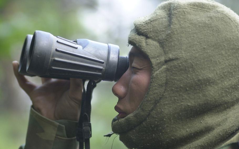 A soldier looks through binoculars