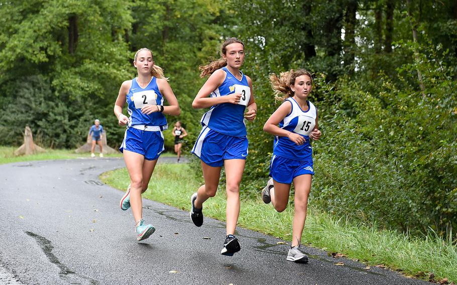 Wiesbaden runners, from left, Kendall Kaloostian, Bryce Watts and Isabella Chambers round a corner on their first lap of the girls 3.1-mile cross country race at Vilseck, Germany, Saturday, Sept. 10, 2022. 