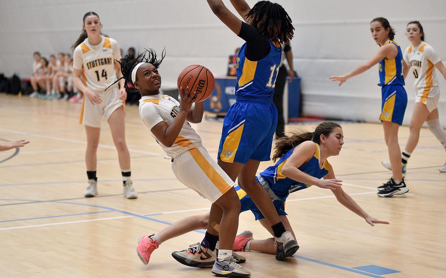 Stuttgart senior Macayla Hines loses her balance after bumping into Wiesbaden junior Kariyah Housey, center, as Warriors Katie Shea falls to the ground during pool-play action of the DODEA European basketball championships on Feb.14, 2024, at the Wiesbaden Sports and Fitness Center on Clay Kaserne in Wiesbaden, Germany.