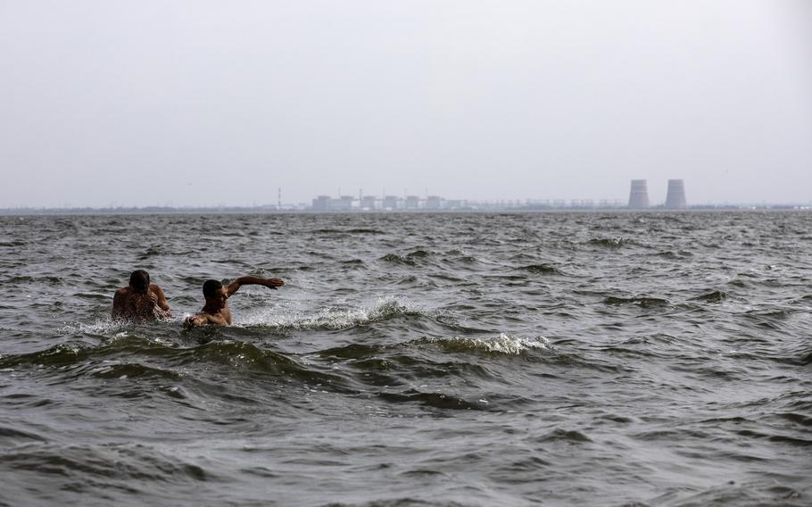 Men swim in Ukraine's Dnieper River on Aug. 15, 2022, across from the Zaporizhzhia nuclear complex, which is under the control of Russian forces. 