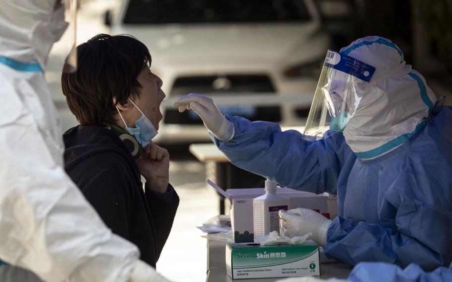 A worker in personal protective equipment collects sample from a resident for a COVID-19 test in a neighborhood placed under lockdown in Shanghai on April 4, 2022. 