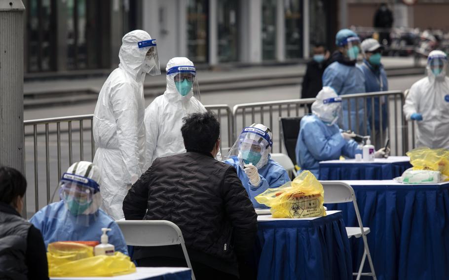 Health workers tests for COVID outside of a clothing market in Shanghai on March 10 2022. 