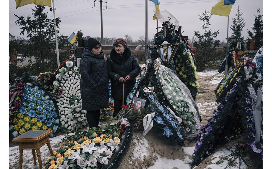 People attend a ceremony at the “Alley of Heroes,” a section of the cemetery in Bucha, Ukraine, where Ukrainian soldiers killed in the past year have been buried.